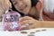 Close up of a coin in the hand,Smiling asian child girl putting coin into piggy bank,feel happy,saving money for the future in