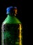 Close up of cold green plastic bottle with texture of water drops and frost isolated on black background