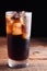Close up on a cold refreshing soft drink with ice on a dark wooden background