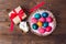 Close up of colored eggs in wicker basket , gift and bunny over wooden background