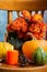 Close-up of colored pumpkins, candle and orange flowers on antique chair, gray background