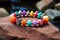 a close-up of a colorful beaded bracelet on a textured granite rock