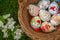 Close up of colorful decorted hand painted Easter eggs in a basket on grass with cherry bossum