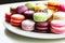 Close-up of colorful macaroon cakes on a white plate. Delicious dessert