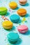 Close up of colorful macaroons, sugar sprinkles and party ribbons over blue background.