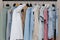 Close-up of a colorful variety of shirts, T-shirts and blouses on hangers inside the closet. boutique of pastel-colored