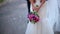Close Up of Colorful Wedding Bouquet at Bride\'s Hands and Groom on Background