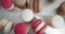 Close up of colorful white, red, and caramel chocolate macarons dessert, filling with tasty ganache, on the table at
