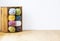 Close-up of a colorful yarn stack in a wooden crate by a white wall and copy space. Real photo.