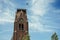 Close-up of commercial airplane flying in sunny blue sky and brick steeple at Weesp.