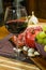 Close up composition of pomegranate, yellow muscat grape, salami, glass of red wine and garlic on a wooden board