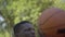 Close-up of concentrated African American sportsman throwing ball into basketball hoop. Portrait of determined young man