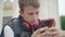 Close-up of concentrated boy using social media on smartphone. Portrait of absorbed Caucasian schoolboy messaging online