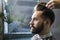 Close up of a concentrated brown haired businessman having his hair combed in a barber shop.