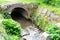 Close-up concrete semicircular arch of a water drain well, a stream flows into a canal, sewage drains, the concept of a drainage