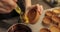 Close-up of the confectioner\'s hands smearing tartlets with a cooking brush.