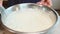 Close-up of a confectioner whipping cream with a whisk to firm peaks in a stainless steel bowl