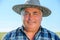 close up of a Content mature farmer in countryside in hat looking at camera