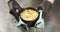 Close-up of cook hands in gloves serving delicious onion soup with cheese crust in a pot