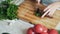 Close up cook hands with knife cutting parsley on wooden board. Concept greens