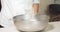 Close-up of cook`s hands pouring dry white rice into a large bowl. The process of cooking asian food