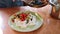 Close-up of cook serving mashed potatoes prepared with herbs in white plate.