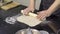 Close-up of cook thinly rolling out dough with rolling pin. Art. Professional chef rolls out dough for thin dish