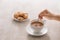 Close up of cookie and hand stirring cup of tea/coffee