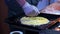 Close-up cooks hands adding up shredded cheese to a pizza dough.