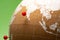 Close up cork globe with red pin on India on green background.