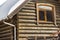 Close-up of corner of new wooden warm ecological cottage house roof covered with snow with steel gutter rain system. Professional