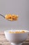 Close-up of cornflakes in spoon over breakfast bowl on table against gray background with copy space