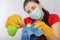 Close-up of a coronavirus model in the hands of a cleaning lady. A housewife in a mask and gloves holds a atomizer and rag.