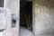 Close up of corroded green door handle and the entrance to a dark stairway in an abandoned building