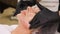 Close-up, cosmetologist in black medical gloves applies cleansing foam to female face with massage movements. skincare