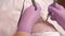Close-up of cosmetologist`s hands in purple gloves smooth wrinkles with the help of two electrodes. Cosmetic procedure