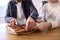 Close Up Of Couple In Kitchen At Home Cutting Homemade Pizza Sitting At Counter