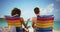 Close-up of couple sitting on beach chairs looking at water horizon