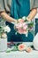 Close-up on creative florist work. Female arranging a bouquet with flowers use florist tools standing by workplace in shop.