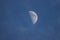 Close up of the crescent moon in the daytime with blue sky