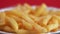 Close-up of crispy appetizing fried fries. Fried potato slices in a plate on a bright background rotate. Selective focus, shallow