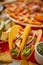 Close up on crispy tacos with various freshly made Mexican foods assortment