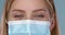 Close up and crop frame of young woman posing in medical face mask. Looking at camera with smile