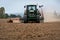 Close-up of crop with Tractor ploughing field.