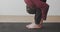 Close up crop view of man stretching legs in uttanasana asana on mat indoors handheld device. Detailed side shot of