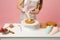 Close up cropped chef cook confectioner or baker in white t-shirt cooking at table isolated on pink pastel background in
