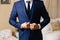 Close-up of a cropped frame of a business stylish man buttoning his jacket, standing in a stylish office with designer