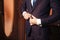 Close-up of a cropped frame of a business stylish man buttoning his jacket, standing in a stylish office with designer