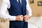 Close-up of a cropped frame of a business stylish man buttoning his jacket, standing in a stylish office with designer