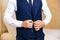 Close-up of a cropped frame of a business stylish man buttoning his jacket, standing in a stylish office with designer